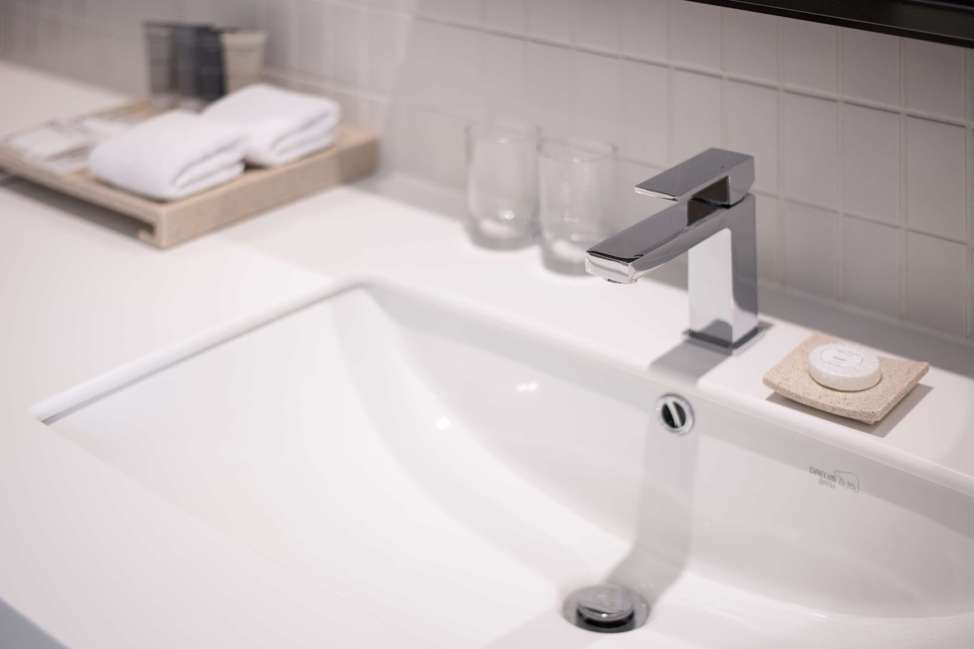 Ein modernes Badezimmer mit einem weißen Waschbecken, einem Chrom-Wasserhahn und einer Seifenschale.