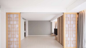 A modern hotel room with a minimalist design, featuring a wooden floor, a television on a wooden stand, and a sliding door with a geometric pattern. - Orakai Daehakro Hotel, BW Signature Collection (Seoul)