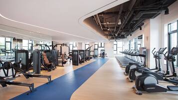 A modern gym with cardio machines, weight stations, and a blue running track.