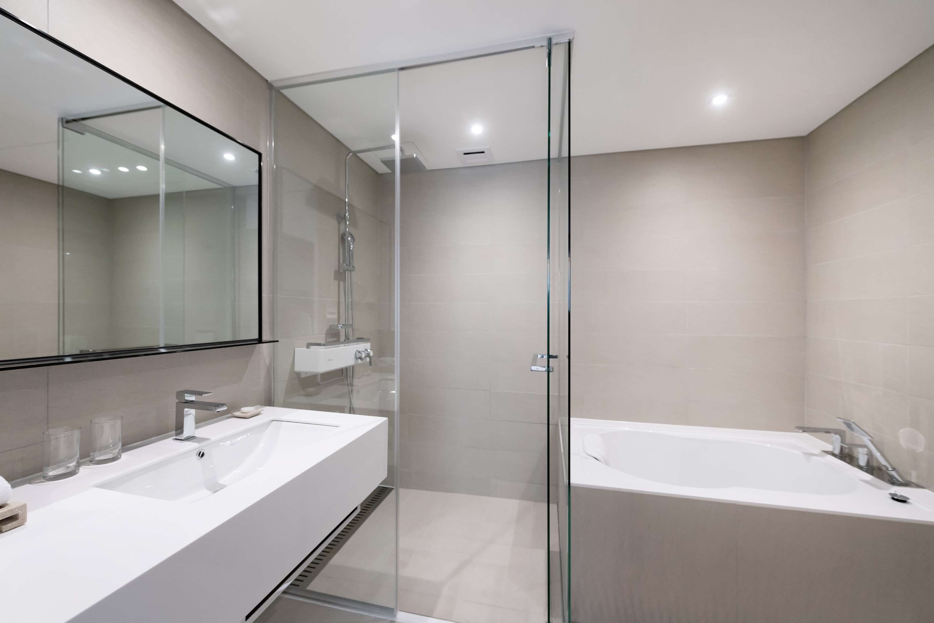 A modern bathroom with two sinks, a glass-enclosed shower, and a standalone bathtub.