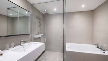 A modern bathroom with two sinks, a glass-enclosed shower, and a standalone bathtub.