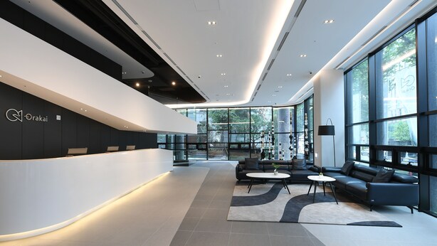A modern reception area with a curved white reception desk, black sofas, and a large window offering a view of the outdoors. - Orakai Daehakro Hotel, BW Signature Collection (Seoul)