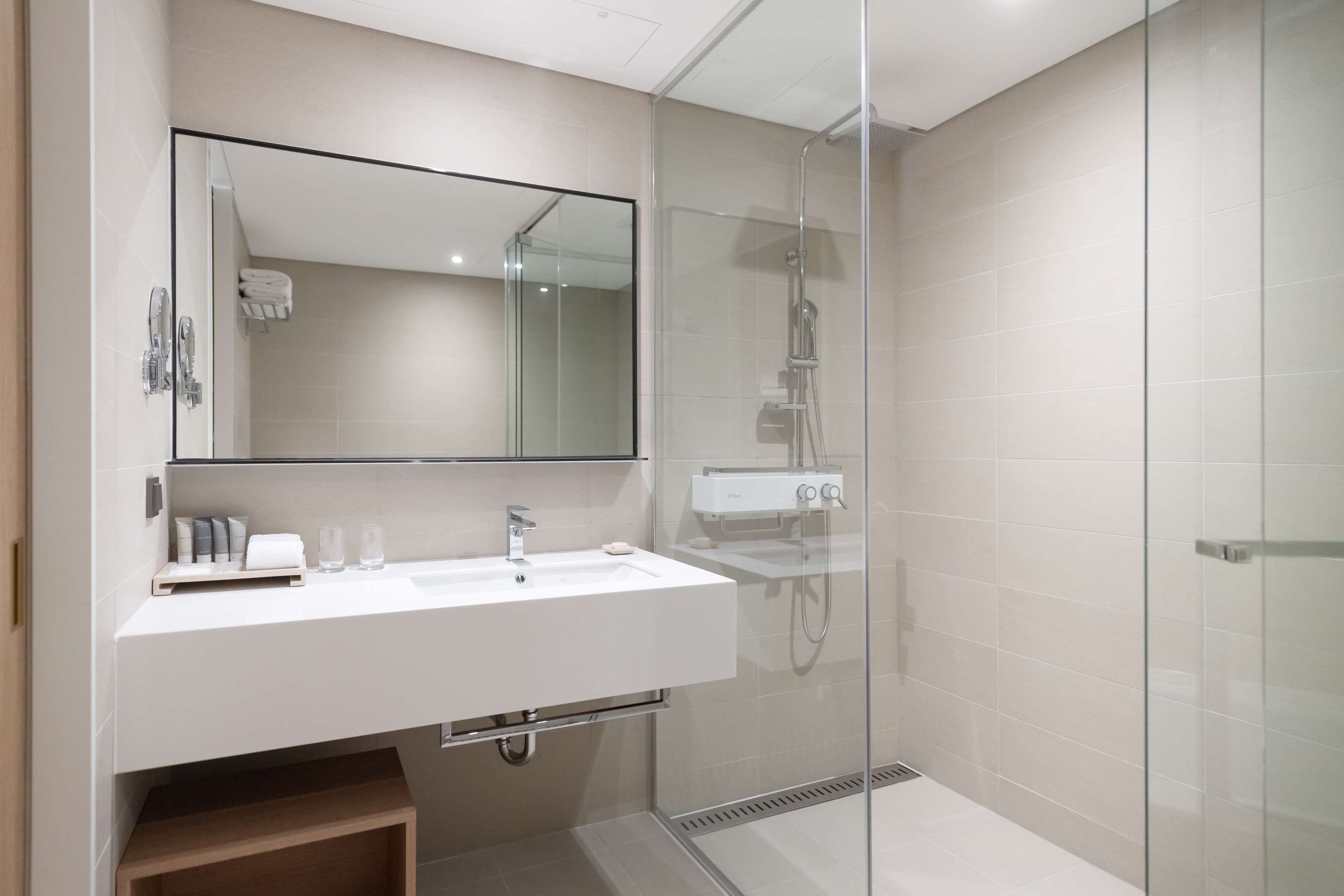 A modern bathroom with a glass-enclosed shower, a white sink, and a large mirror.