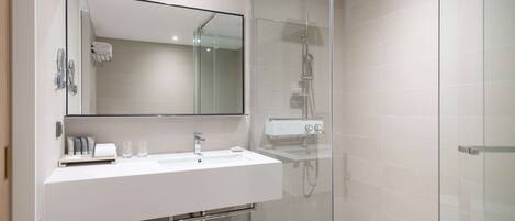A modern bathroom with a glass-enclosed shower, a white sink, and a large mirror.