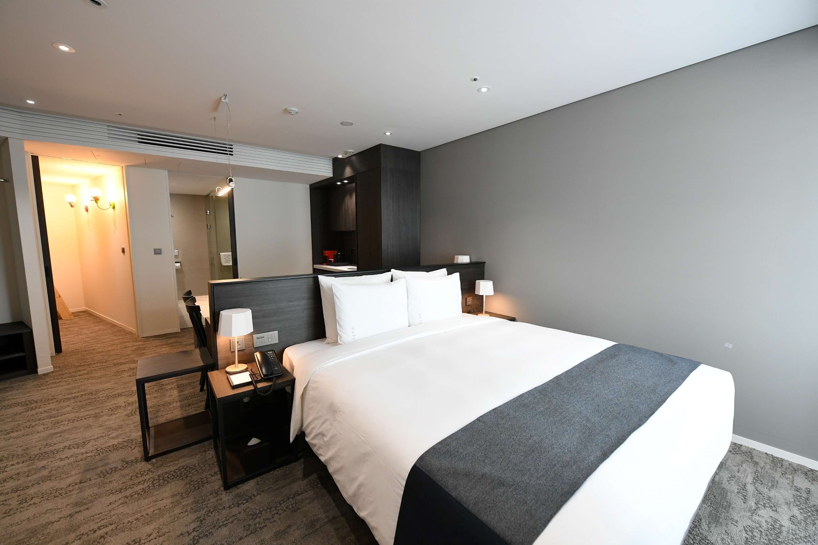 Une chambre d’hôtel moderne, dotée d’un grand lit, de tables de chevet, d’un bureau et d’une armoire.
