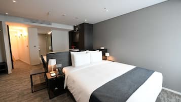 Une chambre d’hôtel moderne, dotée d’un grand lit, de tables de chevet, d’un bureau et d’une armoire.