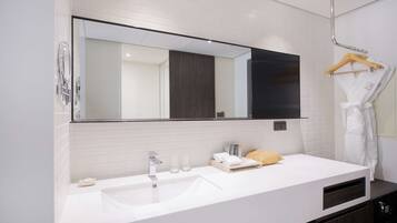 A modern bathroom with a large mirror, white tiles, a sink, and a towel rack.