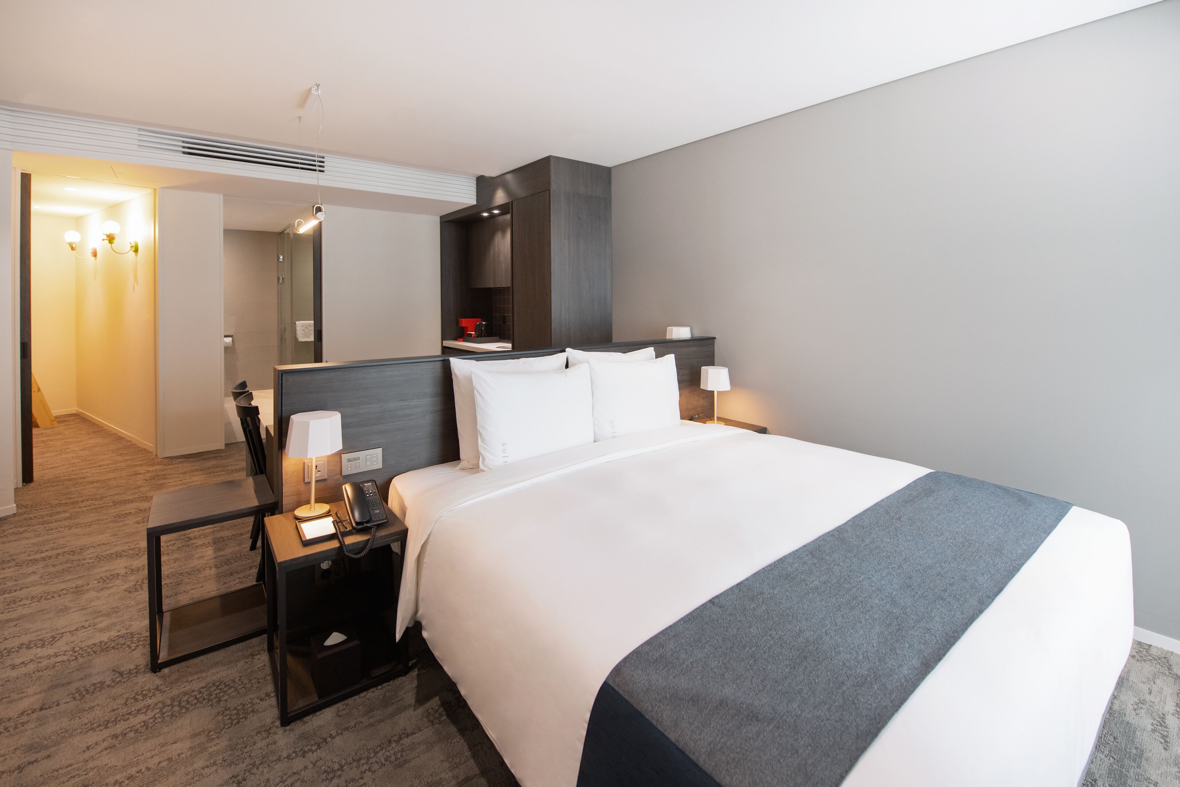 A hotel room with a large bed, bedside tables, a desk, and a mirror.