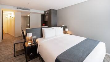 A hotel room with a large bed, bedside tables, a desk, and a mirror.