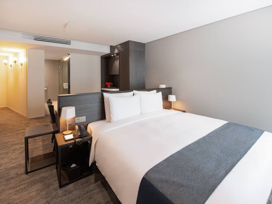 A hotel room with a large bed, bedside tables, a desk, and a mirror.