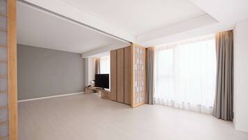 A spacious room with a large window, a television, and a sliding door.