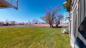A grassy yard with a pond, trees, and a building with a spiral staircase. - Jo's Hideaway, for Lake Erie lovers, fishermen and birders!  Sleeps 4 (Oak Harbor)