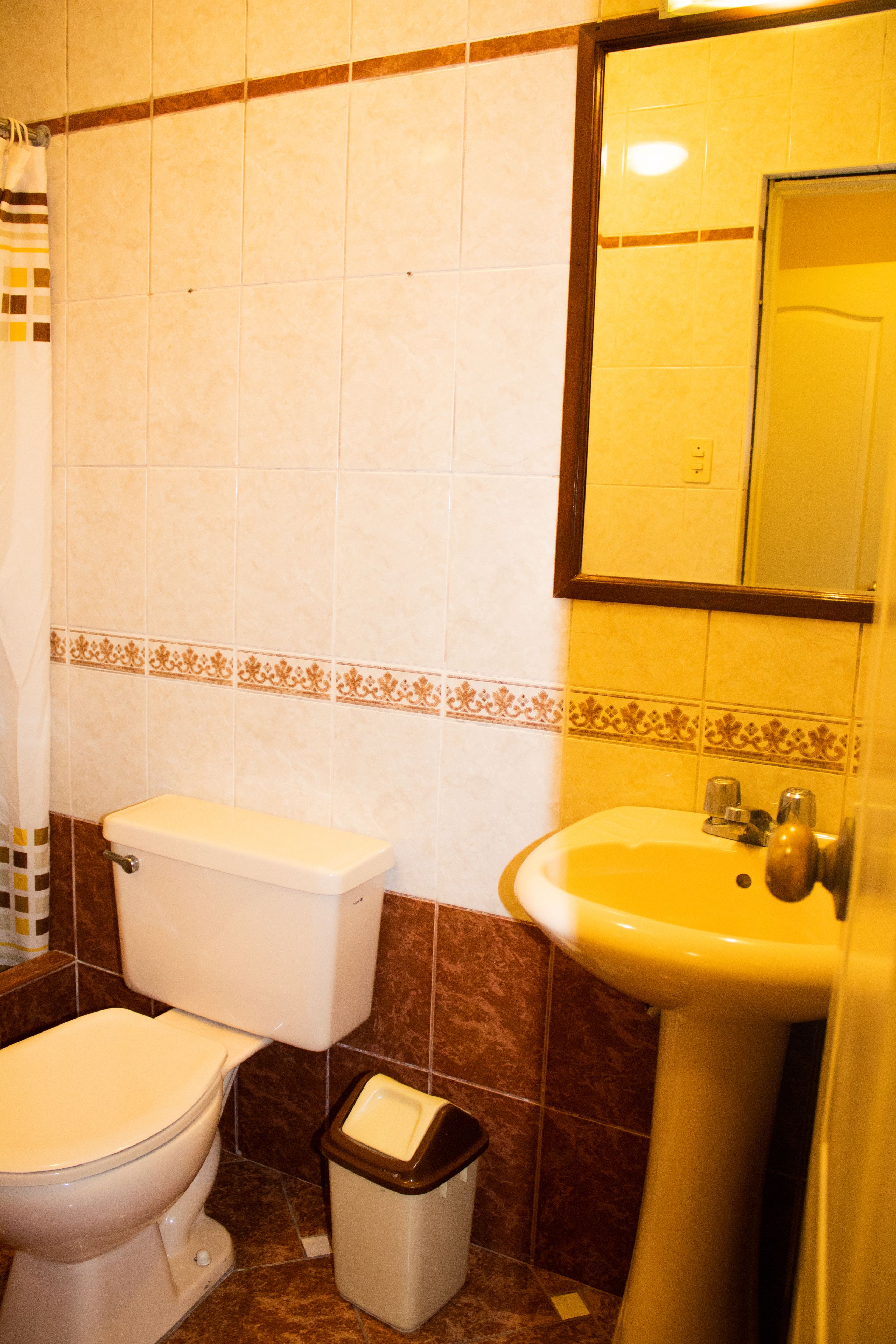 A bathroom with a toilet, sink, and trash bin.