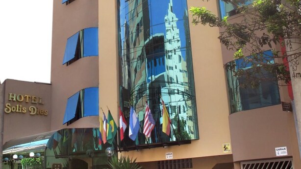 A hotel with a modern facade, large windows, and a prominent mural of a building. - Hotel Solís Dies (Lima)