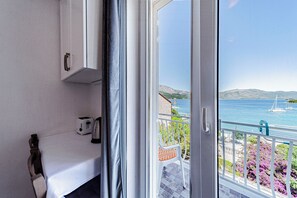 Ein Zimmer mit einer Schiebetür, die auf einen Balkon mit Blick auf das Meer und die Berge führt.