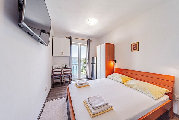 A hotel room with a bed, a desk, a chair, a TV, and a balcony. - S1 - studio just 50m from the beach with sea view (Korčula)