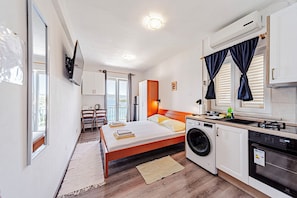 Ein modernes Schlafzimmer mit Bett, Waschmaschine und einer Küchenzeile.