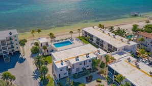 Um hotel à beira-mar com piscina no terraço, vários edifícios e palmeiras.