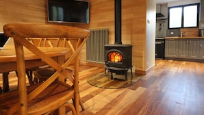 Ein Holzinnenraum mit Kamin, Esstisch und Küchenzeile.
