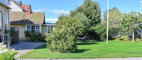 A residential property with a well-maintained lawn, a hammock, and a tall flagpole.