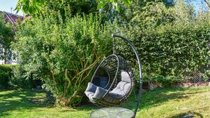 Un jardín con una hamaca colgante y una mesita.