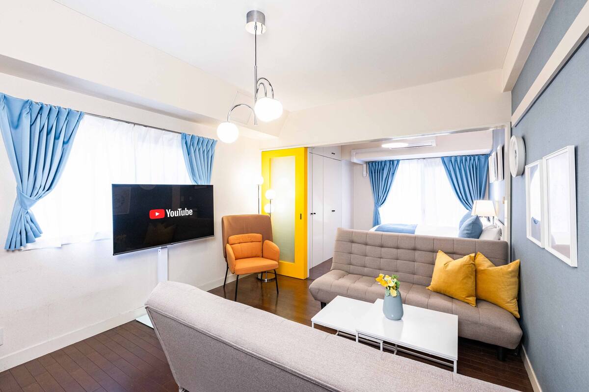 Una sala de estar moderna con un televisor de pantalla plana, un sofá, un sillón y una mesa de centro.