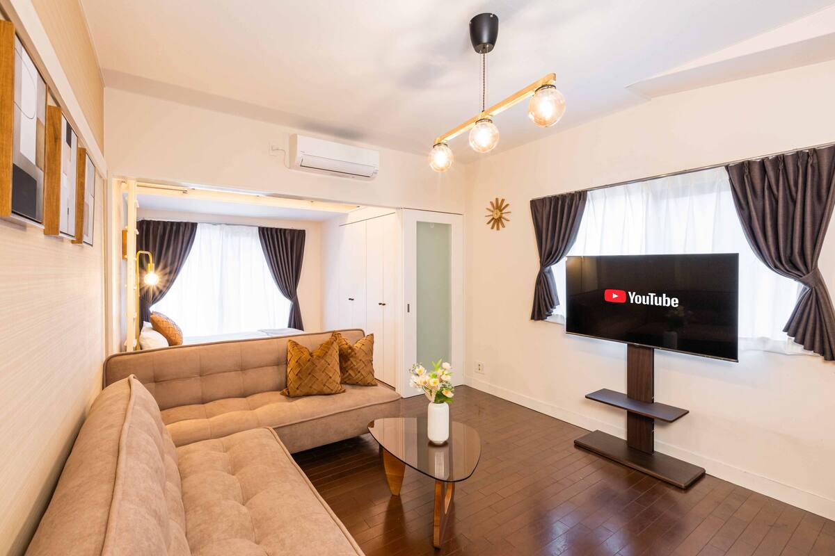 Una sala de estar moderna con un sofá, una mesa de centro, un televisor y un candelabro.