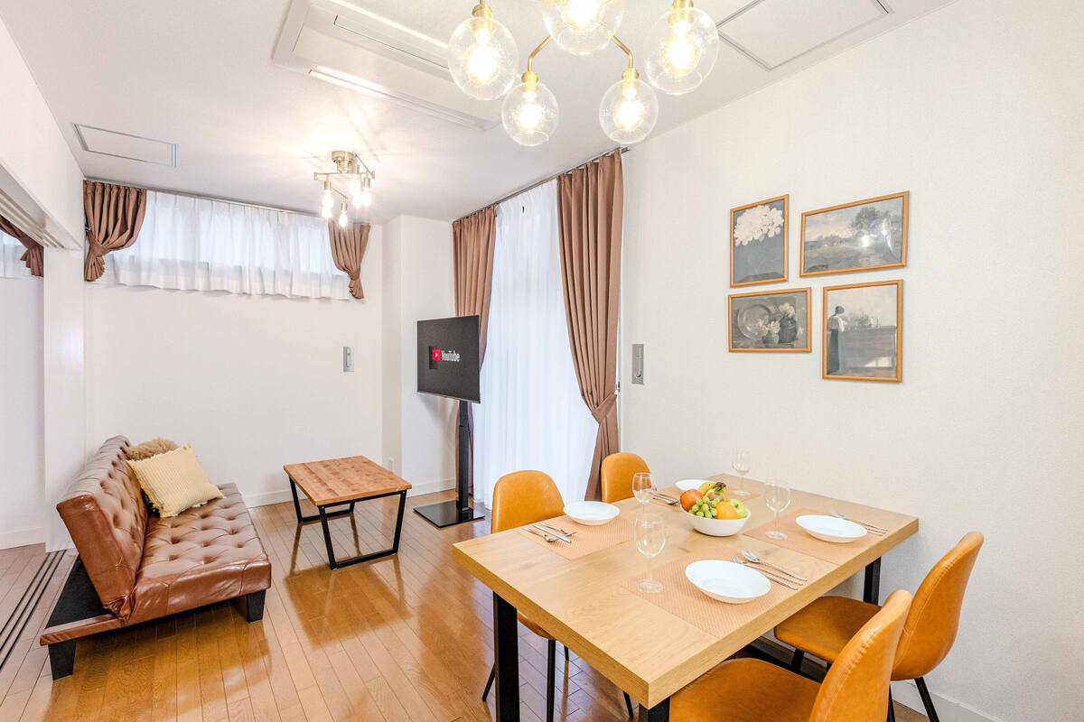 Una sala de estar moderna con un sofá, una mesa de comedor para cuatro personas y un televisor de pantalla plana.