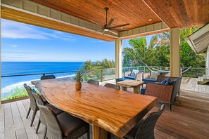 Une terrasse en bois avec une table et des chaises, donnant sur l’océan.