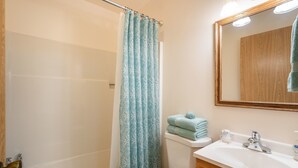 A bathroom with a shower curtain, a toilet, a sink, and a mirror.