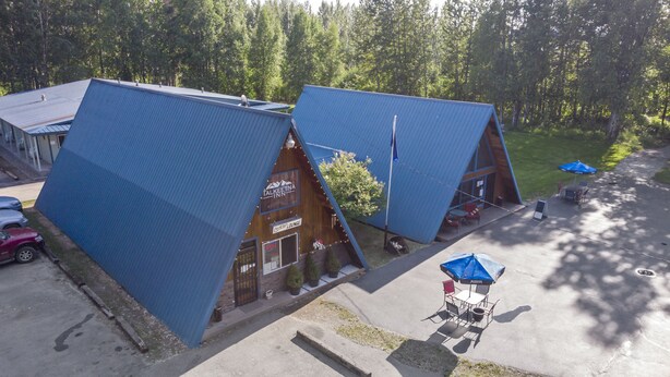 A lodge with a unique triangular roof design, a visible entrance, and outdoor seating with umbrellas.