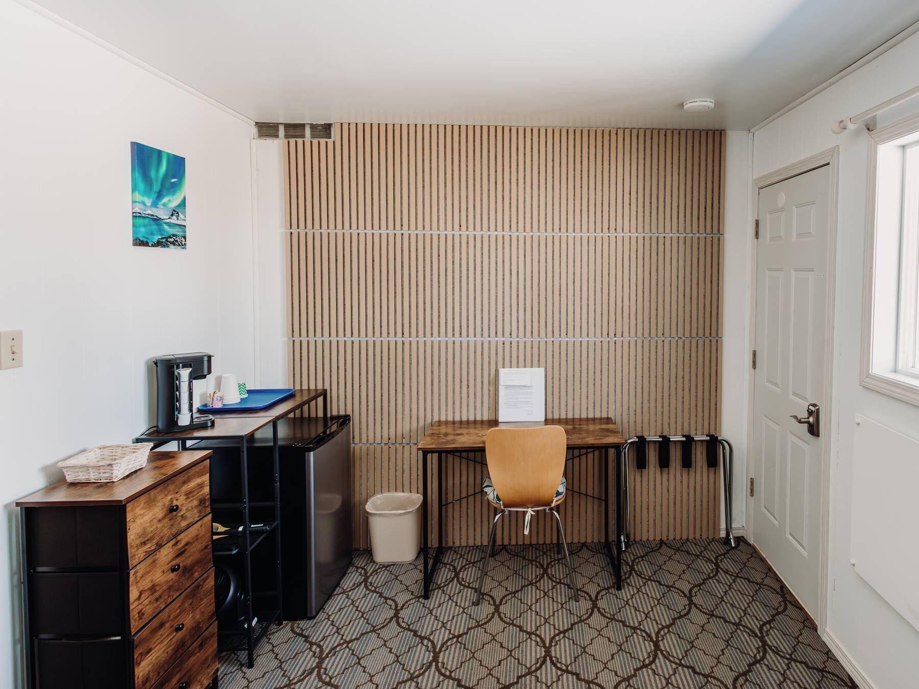 Une chambre d’hôtel compacte, équipée d’un bureau, d’une chaise et d’une petite kitchenette.