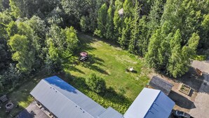 An aerial view of a property with a large lawn, a red lawnmower, and a garden bed.