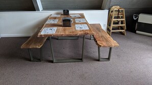 A wooden table with benches in a room with a sloped ceiling and a radiator. - Talkeetna Inn (Talkeetna)