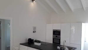 A modern kitchen with white cabinets, a black countertop, and a built-in oven. There are white chairs around the island and a small plant on the countertop. - Villa Buena, fantastic luxury villa with internet/ wifi (Hato)