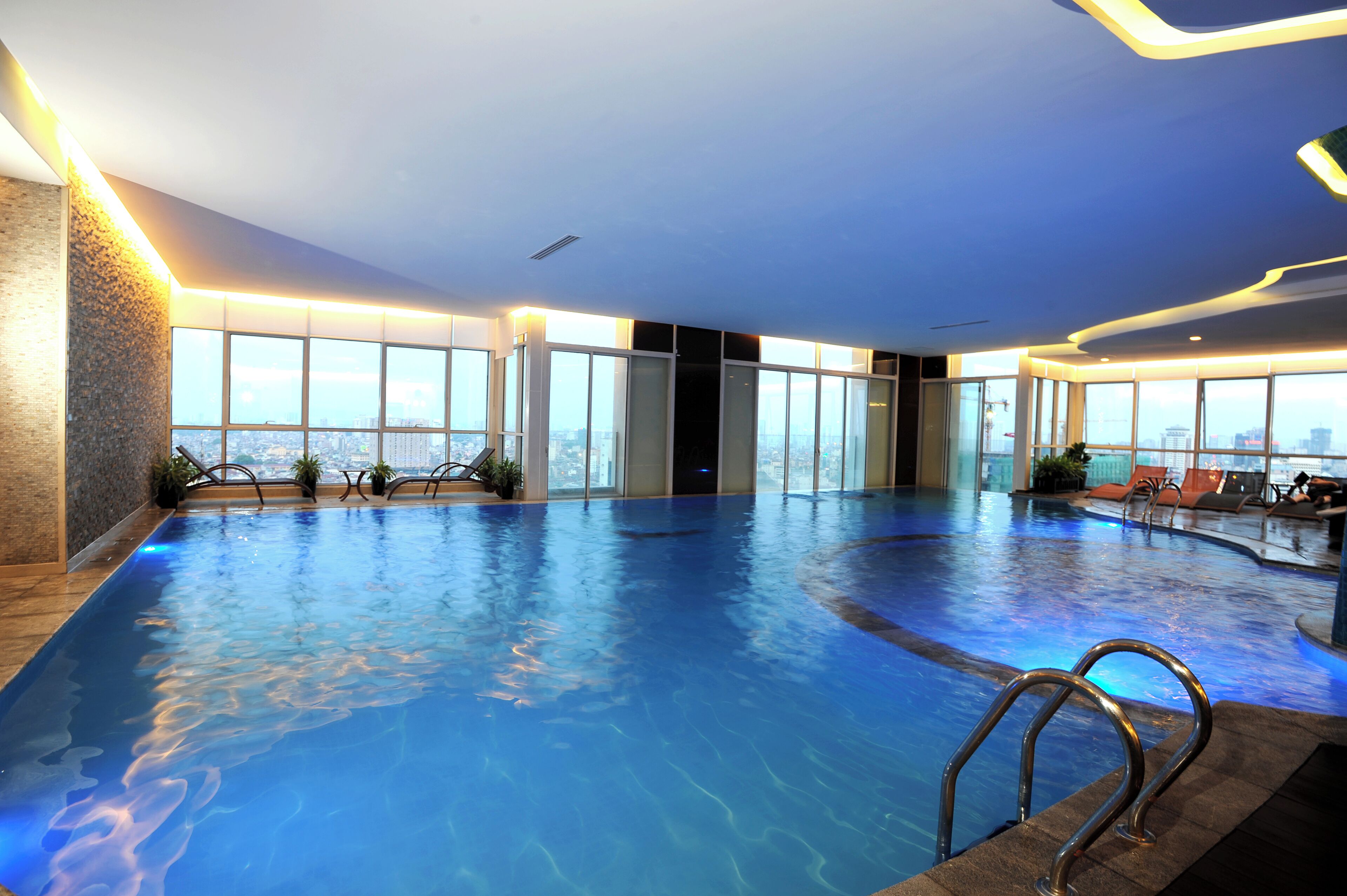 An indoor swimming pool with clear views of the cityscape through large windows.