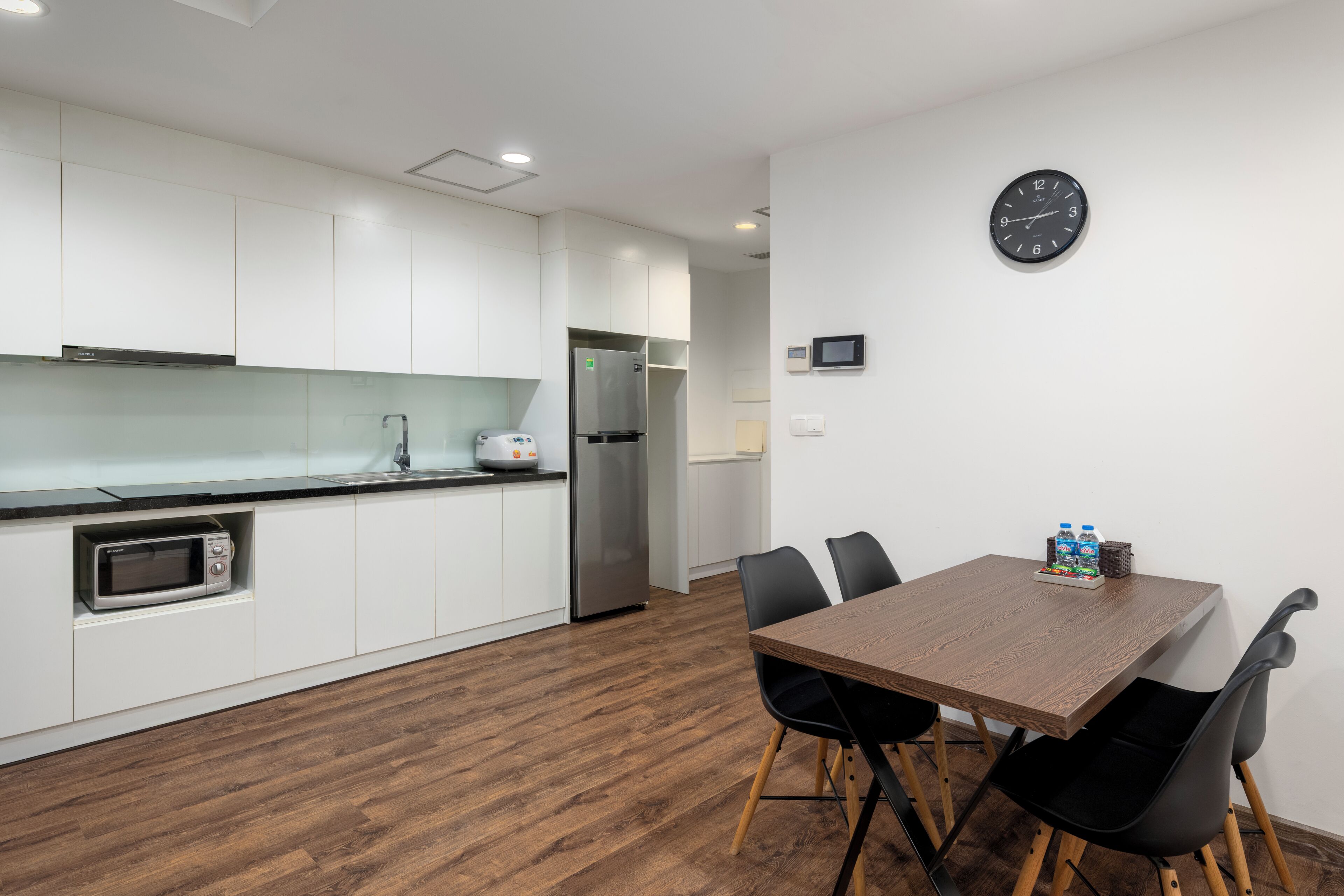 A modern kitchen with white cabinets, a microwave, and a stainless steel refrigerator.