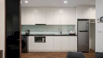 A modern kitchen with white cabinets, a stainless steel refrigerator, a microwave, and a sink.