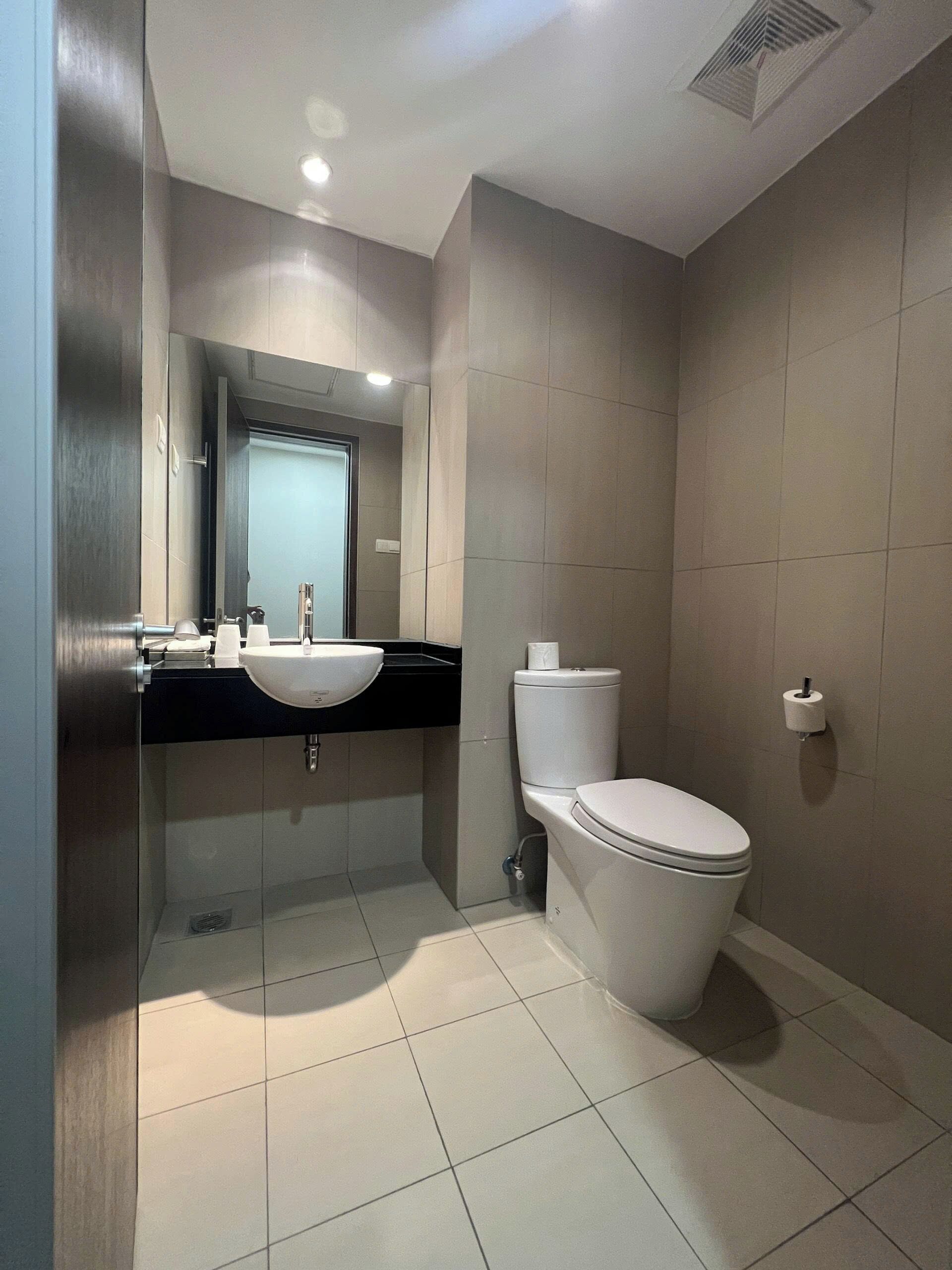 A modern bathroom with a toilet, sink, and mirror.