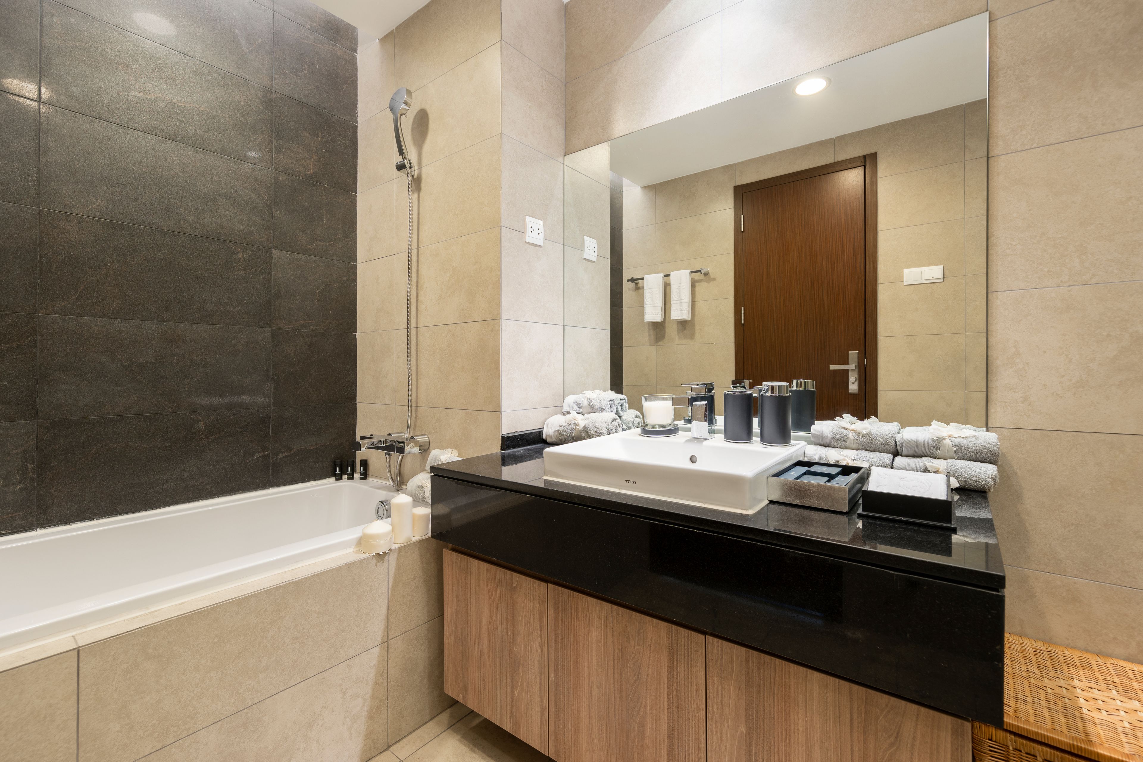 A modern bathroom with a bathtub, a large mirror, and a vanity with toiletries.