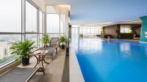A modern indoor pool with clear views of the city, large windows, and comfortable seating areas. - Lancaster Hanoi Service Apartment (Hanoi)