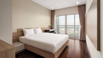 A modern hotel room with a large bed, a desk, and a city view.