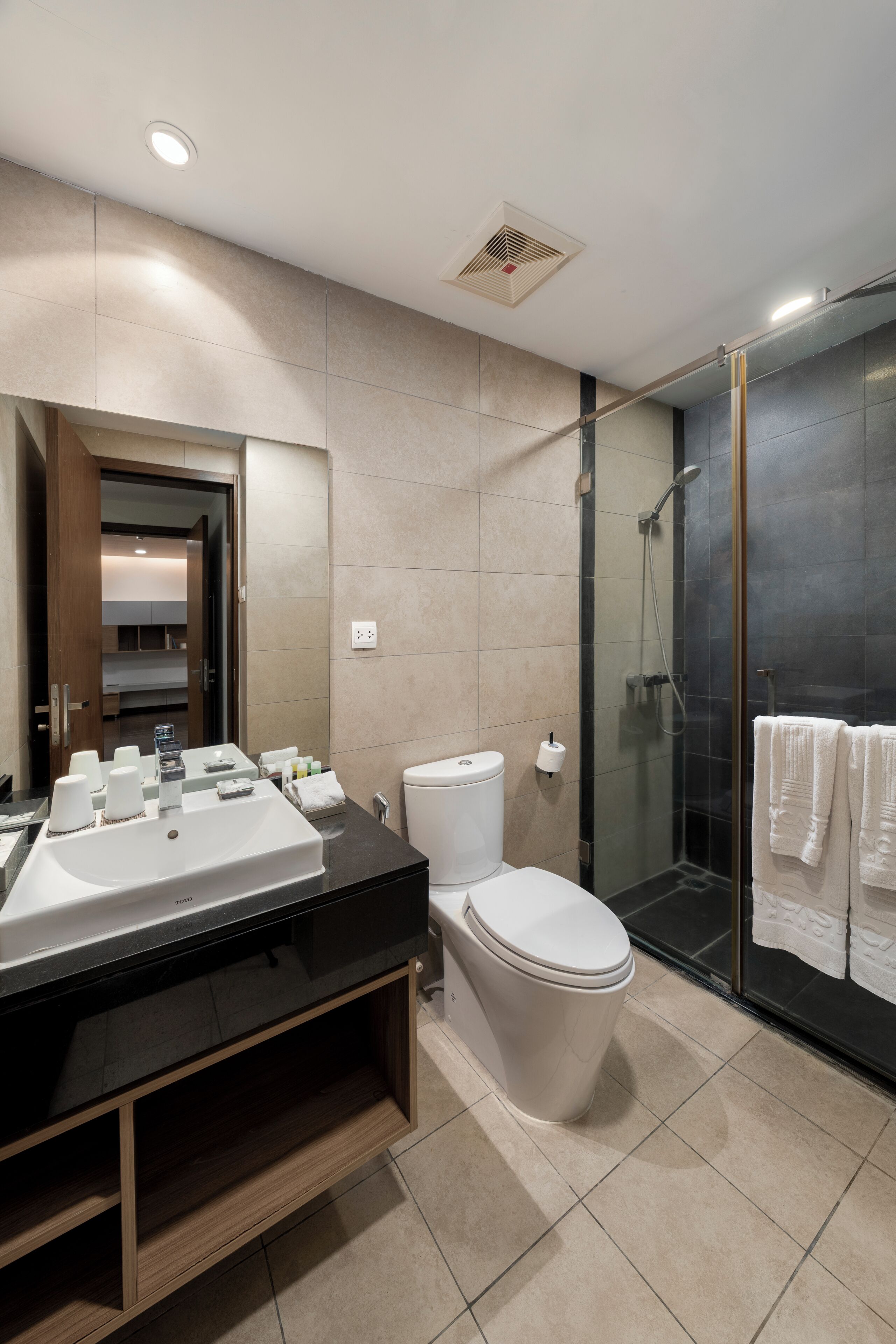 Une salle de bain moderne dotée d’un meuble-lavabo à deux vasques, de toilettes et d’une douche à parois de verre.