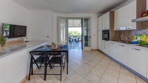 Eine moderne Küche mit Essbereich, Fernseher und Blick auf eine Terrasse.