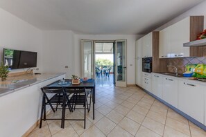 Geladeira, fogão, talheres/pratos/utensílios de cozinha, mesas de jantar