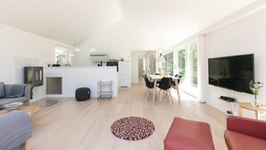 A modern living room with a sofa, a coffee table, a TV, and a dining area with chairs and a table. - 3 bedroom nice home in Hasle (Hasle)