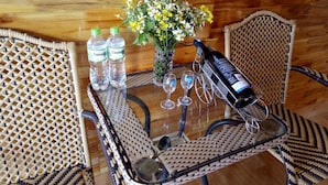 A glass-top table with a bottle of red wine, two water bottles, a vase with flowers, and two wine glasses. - Sau Meo Homestay (Ta Van)