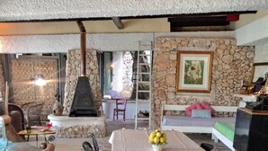 A cozy dining area with a stone floor, a table with a white tablecloth, and a bench with cushions.