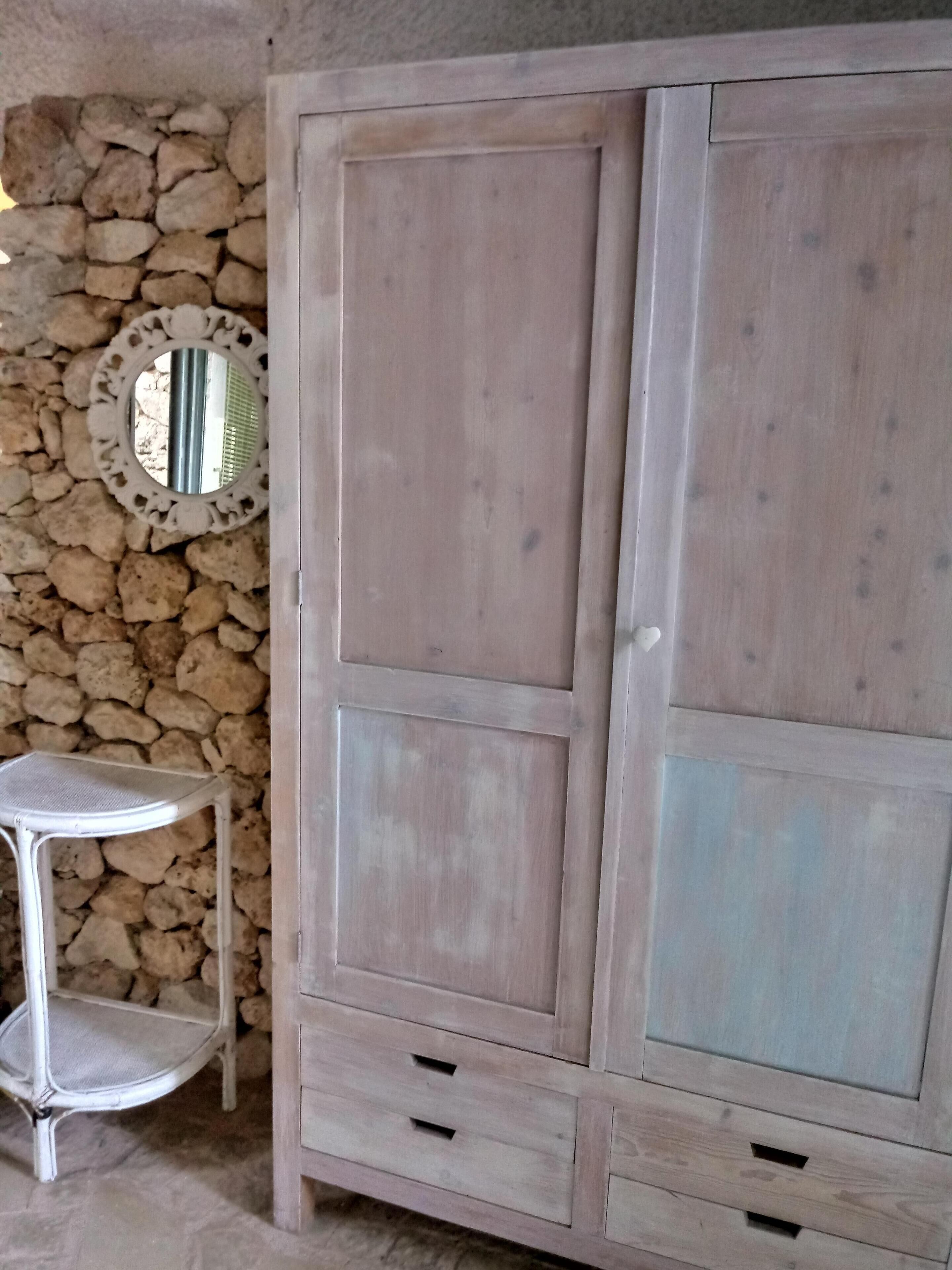 Un armadio con diversi cassetti e uno specchio su un muro in pietra.