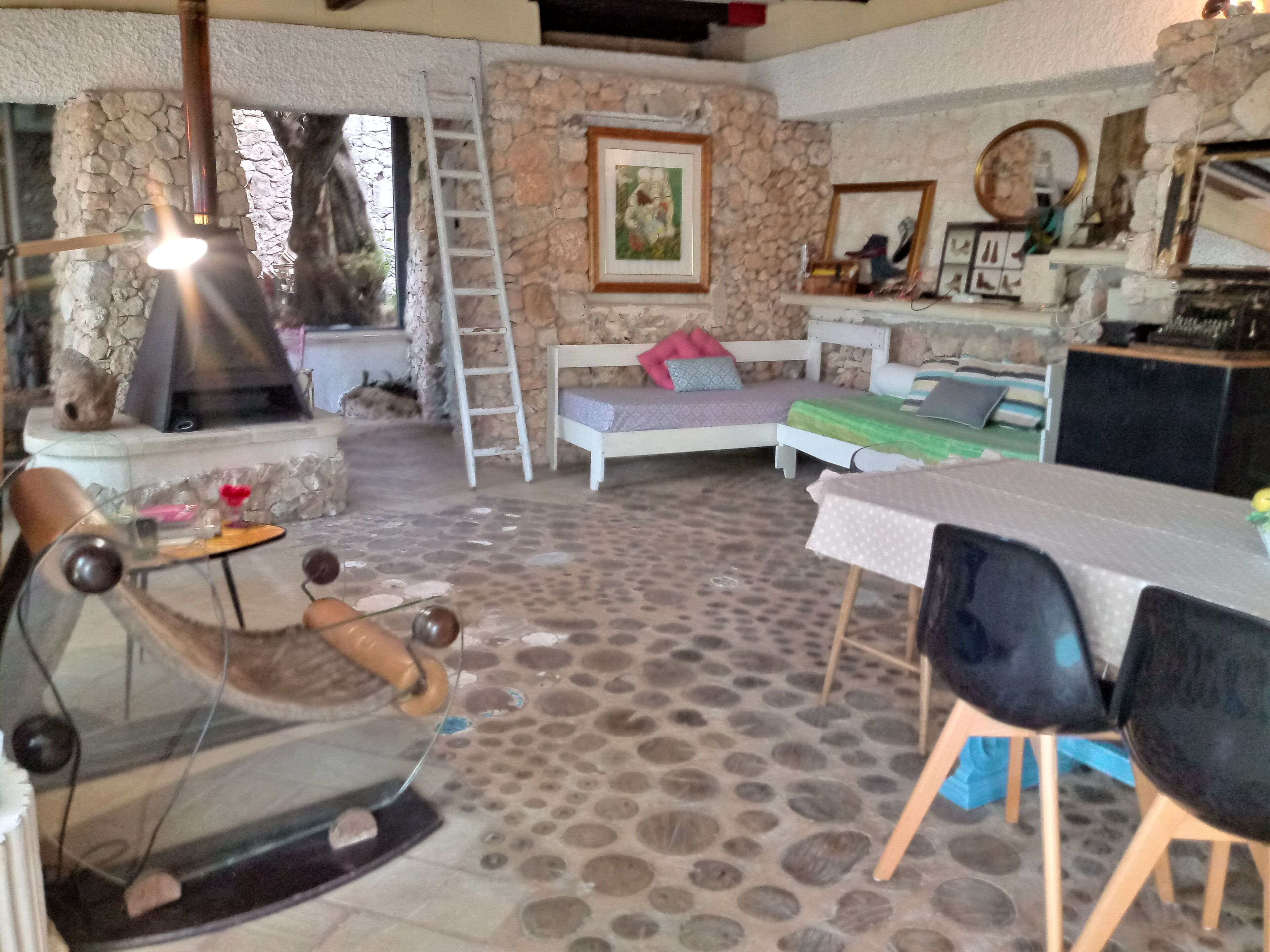Uma área de estar acolhedora com uma parede de pedra, lareira, cama, mesa e uma cadeira.